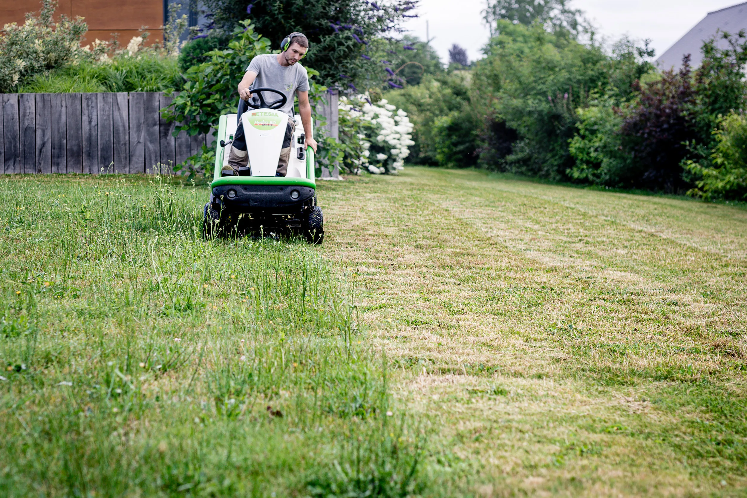 un jardinier en train de tondre une pelouse avec un tracteur